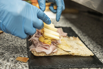 The rough texture of the black granite contrasts with the softness of the focaccia dough, which expert hands begin to gently fold.