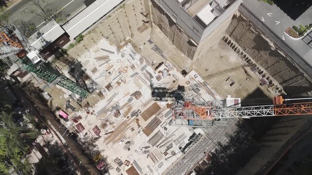 Top-down aerial dolly-forward shot of a large construction site in S&atilde;o Paulo, revealing a deep building foundation, structural excavation, and heavy engineering work. Urban development.