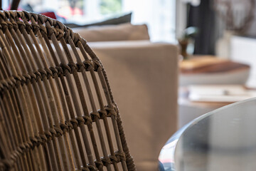 Detail of a room with a wicker chair and a circular glass table