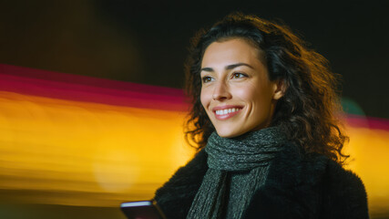 Smiling woman smartphone night city bokeh lights urban street curly hair warm scarf winter coat candid portrait modern lifestyle wireless network digital connection. Confident mood and hope