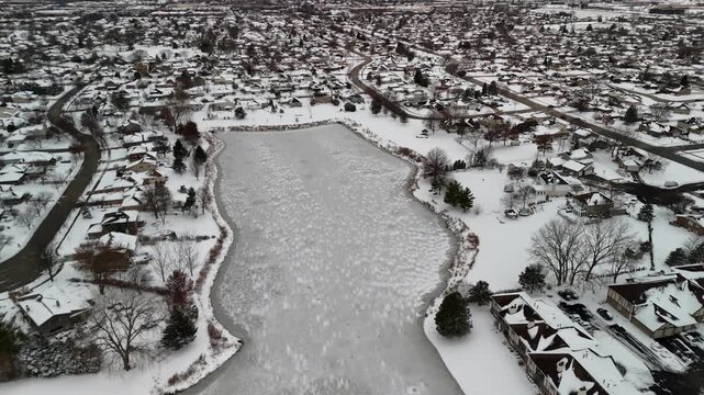 4K Aerial Top-Down View of a Frozen Suburban Pond with Cracked Ice and Fresh Snow in Orland Park, Illinois