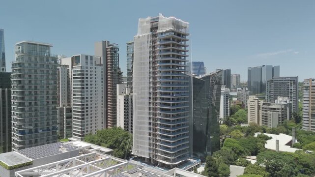 Close-up dolly-in aerial shot of a skyscraper under active construction, showing structural framing, engineering details, and real estate development progress.