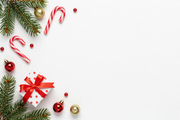 Elegant Christmas holiday background with fir branches, candy canes, sparkling baubles, and a festive gift box on a clean white surface, perfect for seasonal greetings