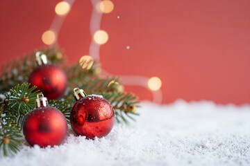Festive red Christmas baubles on sparkling snow with cozy bokeh lights, creating a comfortable holiday season arrangement