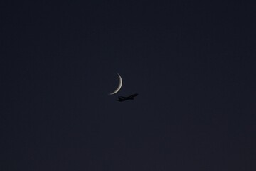 Airplane Silhouette Flying Under Crescent Moon at Night — Minimal Dark Sky Photography