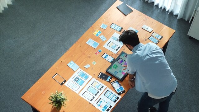 Top view of skilled businessman looking at Ux Ui design in tablet while designing protocol or choosing wireframe interface. Caucasian smart front-end developer planning about UI design. Convocation. - Powered by Adobe