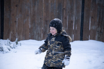 Happy child playing in falling snow during winter