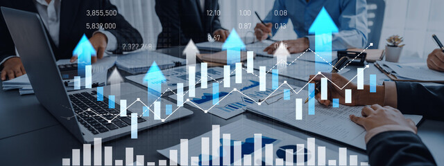 A business team collaborates in a modern office, analyzing financial growth trends using graphs and charts on a laptop, illustrating strategic insights and planning. Scalp