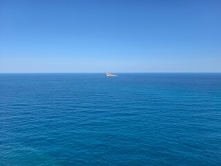 Fototapeta premium tiny isolated island amidst peaceful blue ocean and expansive clear sky inspiring solitude