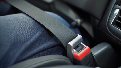 A close-up shot of a person's lap with a buckled seatbelt in a car, emphasizing safety and responsible driving.