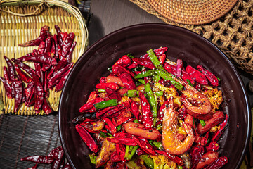 Stir-fried shrimp, sausage, cauliflower, and chili in a dark bowl with sesame seeds and rustic...