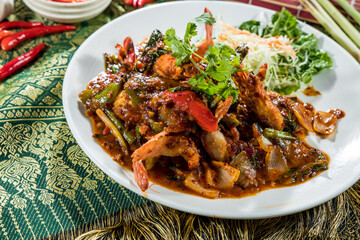 Thai-style stir-fried shrimp with vegetables and herbs, served with salad and styled on traditional fabric.