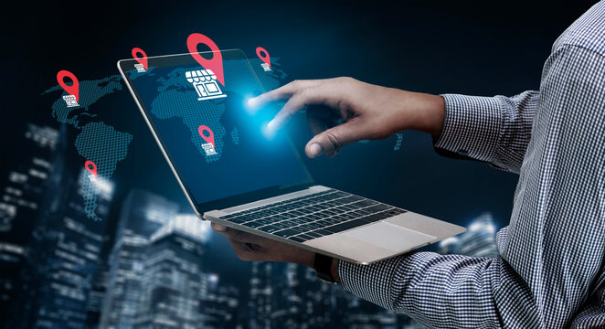 A modern businessman interacts with a laptop displaying an illuminated map and location markers, symbolizing technology, global connectivity, and digital strategy in an urban environment. Gantry