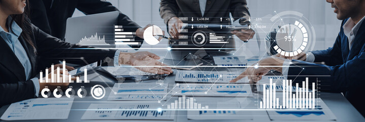 A dynamic business meeting showcasing professionals engaged in discussion, with digital charts and data analysis visible on screens, illustrating modern corporate communication. Scalp