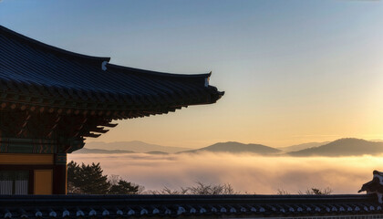 Traditional Korean palace eaves silhouette over mountain range and sea of clouds at sunrise