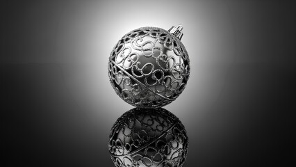 Elegant silver Christmas ornament with intricate filigree design on reflective surface.