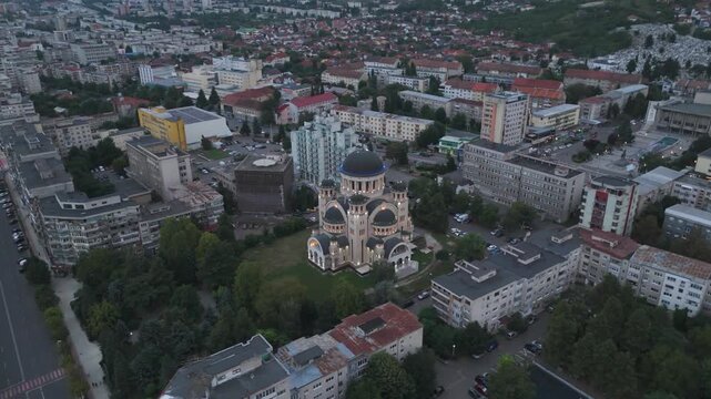 A stunning nighttime aerial view of Catedrala Adormirea Maicii Domnului in Deva, beautifully illuminated against the dark city.