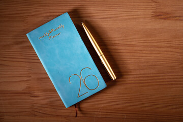 2026 planner and gold colored pen on wood background