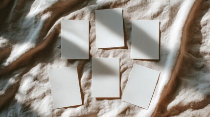 A minimalist arrangement of six blank cards on a textured fabric, illuminated by soft natural light.