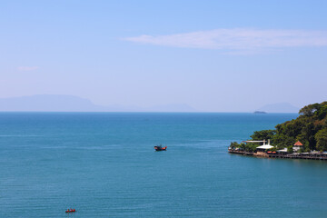 Tropical seascape view with deep blue ocean, distant mountains, and coastal waterfront resort.