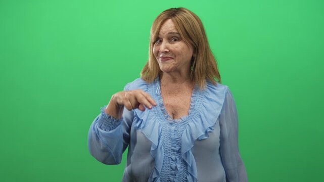 Middle age woman with blonde hair and blue blouse showing one two three finger count with raised hand and smirk in studio; playful counting.