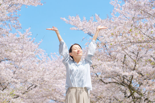 桜の前で深呼吸する女性 - Powered by Adobe