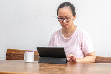 Indonesian woman is working with at a digital tablet and a cup of coffee at home