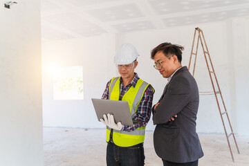 Construction professionals reviewing project plans on a laptop in a newly built interior space with safety gear and tools in view