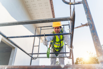 Construction Worker on Scaffolding Wearing Safety Gear and Helmet Engaged in Building Project Outdoor During Daylight Hours