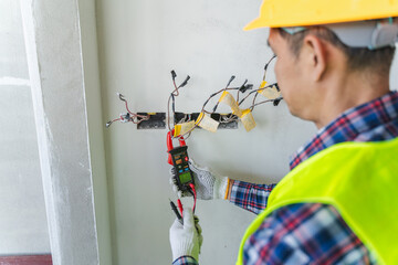 Electrician Testing Electrical Wiring with Multimeter in Construction Site for Troubleshooting and...