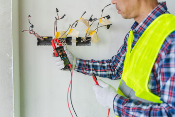 Electrician Using Multimeter to Test Electrical Wiring Safety in Construction Site with Professional Gear and Precautionary Measures for Quality Assurance
