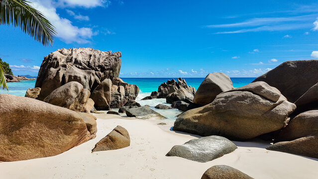 White sand beach with massive granite rocks and clear turquoise ocean waves crashing against the shore. Anse Patates. Seychelles, La Digue. - Powered by Adobe