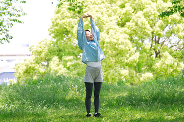 屋外で準備運動をする40代女性