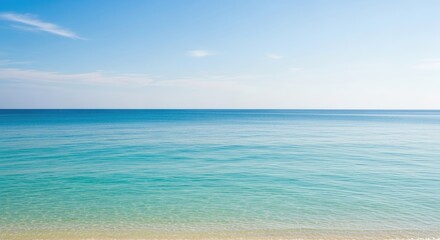 Obraz premium A serene beach scene with clear blue water and a sandy shore.