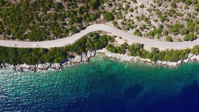4K Drone footage of three cars moving by the sea curved road near a tranquille waves on the Greek coast on Cephalonia island. Transportation, nature concept.