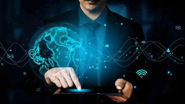 A businessman engages with a tablet, showcasing a digital interface that represents global connections, data visualization, and technological advancement in business. Xenic