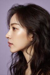Fototapeta premium Graceful Side-Profile Portrait of an East Asian Woman with Wavy Dark Brown Hair and Naturally Glowing Fair Skin in Soft Lilac Light 