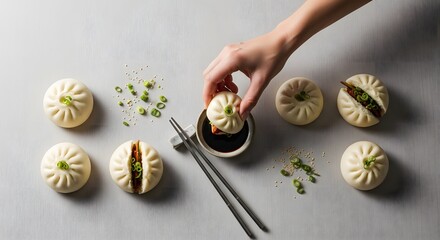 Close-up of a hand dipping a bao bun into a small bowl of sauce with chopsticks.