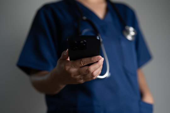 Close-up of healthcare professional with phone in hand, symbolizing e-health, mobile consultation, remote care, and use of digital devices for patient monitoring and medical communication.