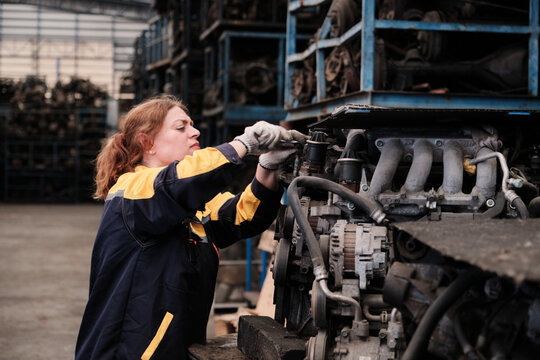 Professional Hispanic mature female mechanic fixing used machines and auto engine spare parts in warehouse stacks, checking distribution stock in manufacturing factory, and industrial worker career.