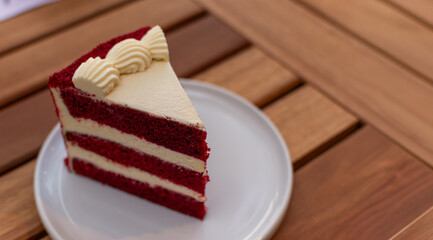 Vista isométrica de una porción triangular perfecta de torta Red Velvet en plato blanco. Contrastan las capas de bizcocho rojo intenso con el relleno de crema blanca.