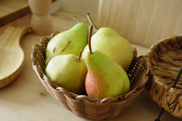 Fresh pears in a wicker basket on a wooden table