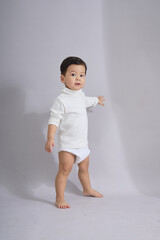 The child stands with hands near the waist.