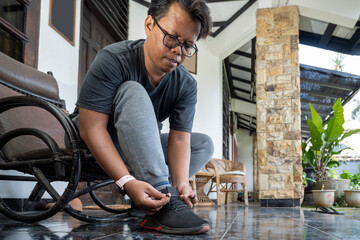 Indonesian southeast asian man is tying his shoelaces before running outdoors. Sport activity