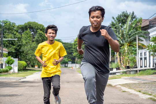Two Indonesian southeast asian men performing a jogging exercise together outdoors. Sport activity