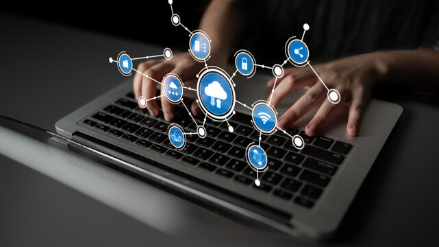 A close-up of hands typing on a laptop keyboard, surrounded by digital icons symbolizing cloud computing and digital connectivity in a modern tech environment. Tessel