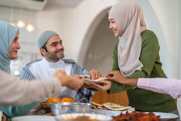 Muslim big family sharing traditional meal together around dining table wearing hijabs and kufi in cultural love, ramadan iftar celebration, eid al-fitr festive, halal meal gathering food culture