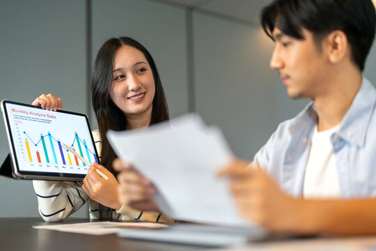 Asian businesswoman startup presenting data summary chart on tablet meeting with colleagues, financial report analysis teamwork strategy planning corporate success at office, marketing, data analytics