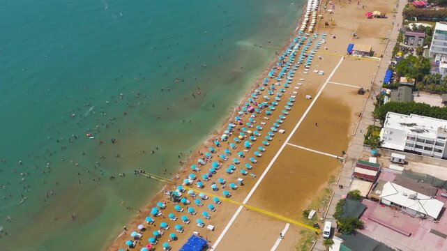 Kizkalesi, Mersin, Turkey. Aerial view of active city beach full of people, swimming, water sports, umbrellas and seaside cafes.. Aerial View, MasterShots, Dronie