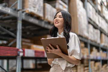 Asian warehouse staff woman checking inventory with clipboard in logistics management, working in supply chain, e-commerce, shipping, warehouse management and distribution center industry business